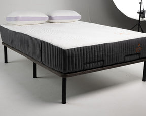 Mattress on a bed frame with pillows on a gray background